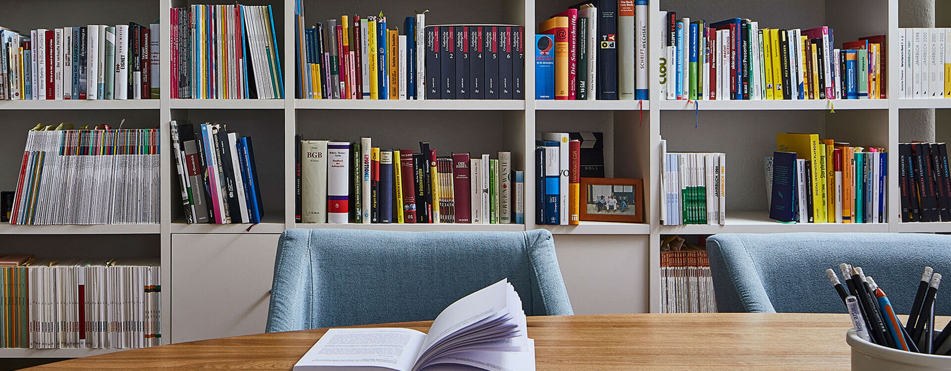 Agentur lege artis - Ein offenes Buch zur Gesundheitskommunikation liegt auf einem Tisch vor einem Bücherregal